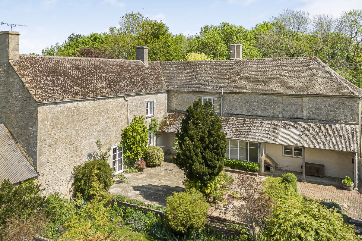 Aerial view of Purwell Farmhouse and its courtyard, surrounded by gardens and trees