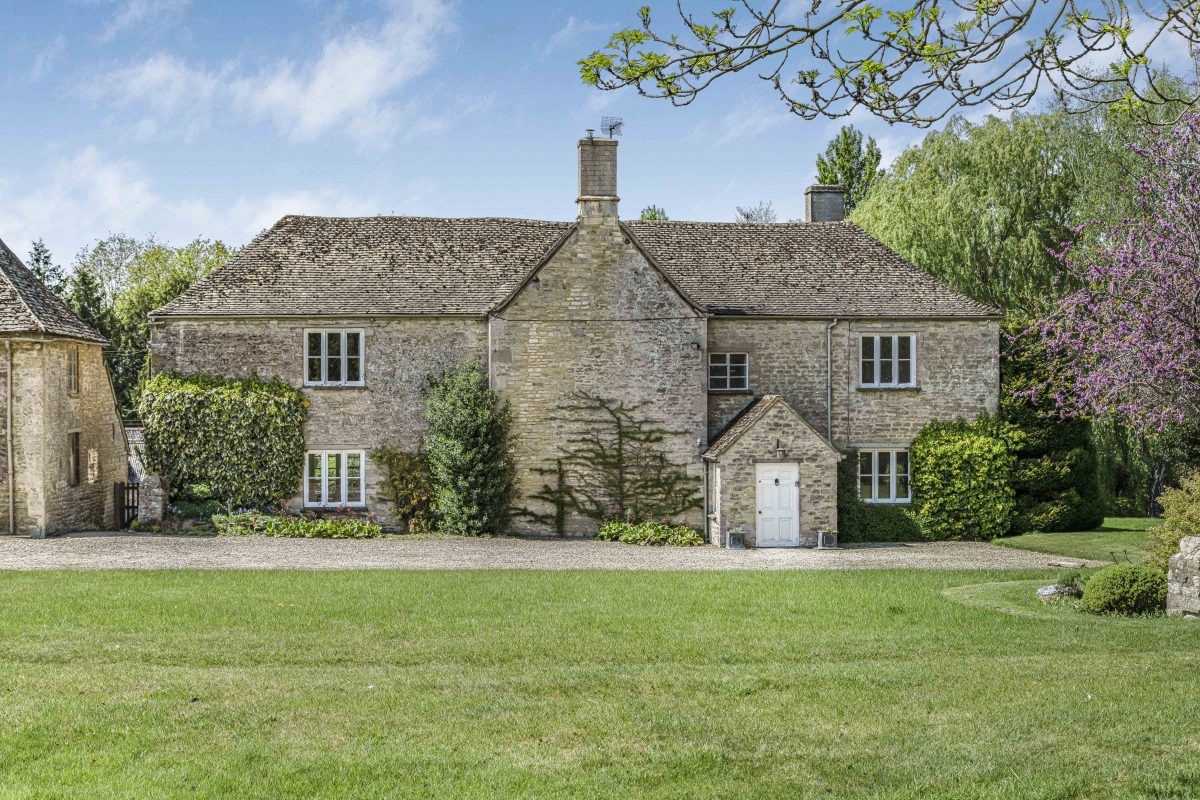 Purwell Farmhouse, a two-storey Cotswold stone farmhouse behind a wide lawn