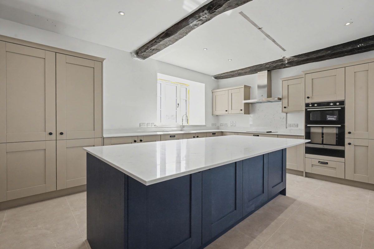 Kitchen at Purwell Farmhouse with a navy island, white worktop and double oven