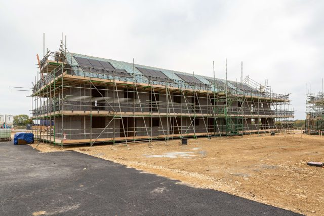 A row of new homes under construction, wrapped in scaffolding