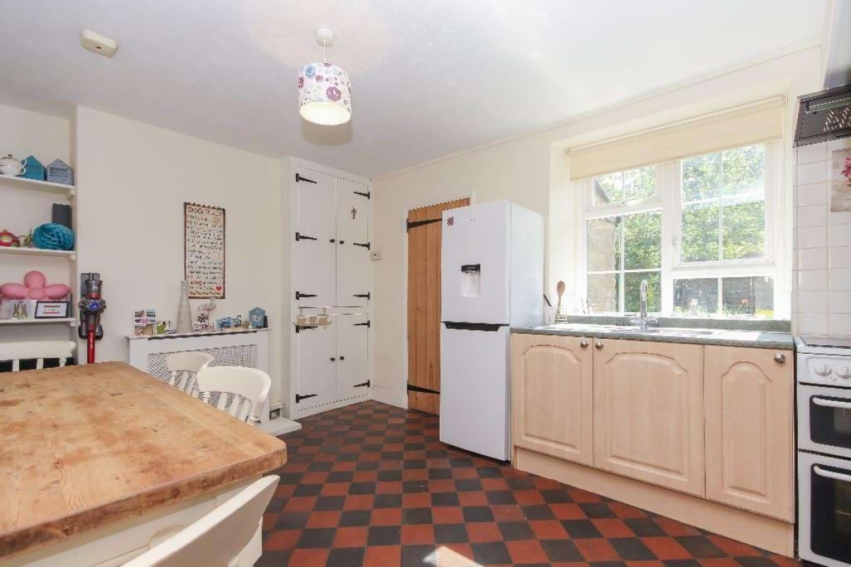 Kitchen at Grove Road with a red and black tiled floor, pine table and white fridge