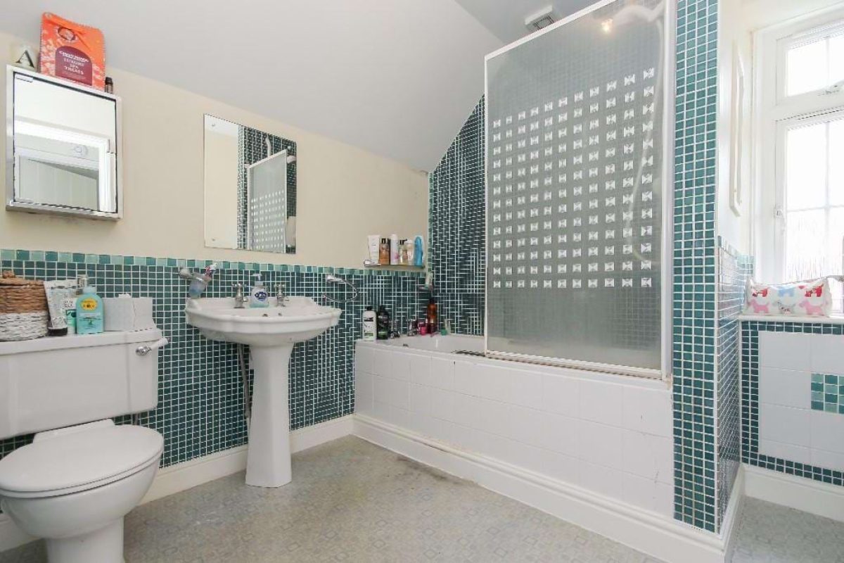 Bathroom at Grove Road with green mosaic tiles, a bath with shower screen and pedestal basin