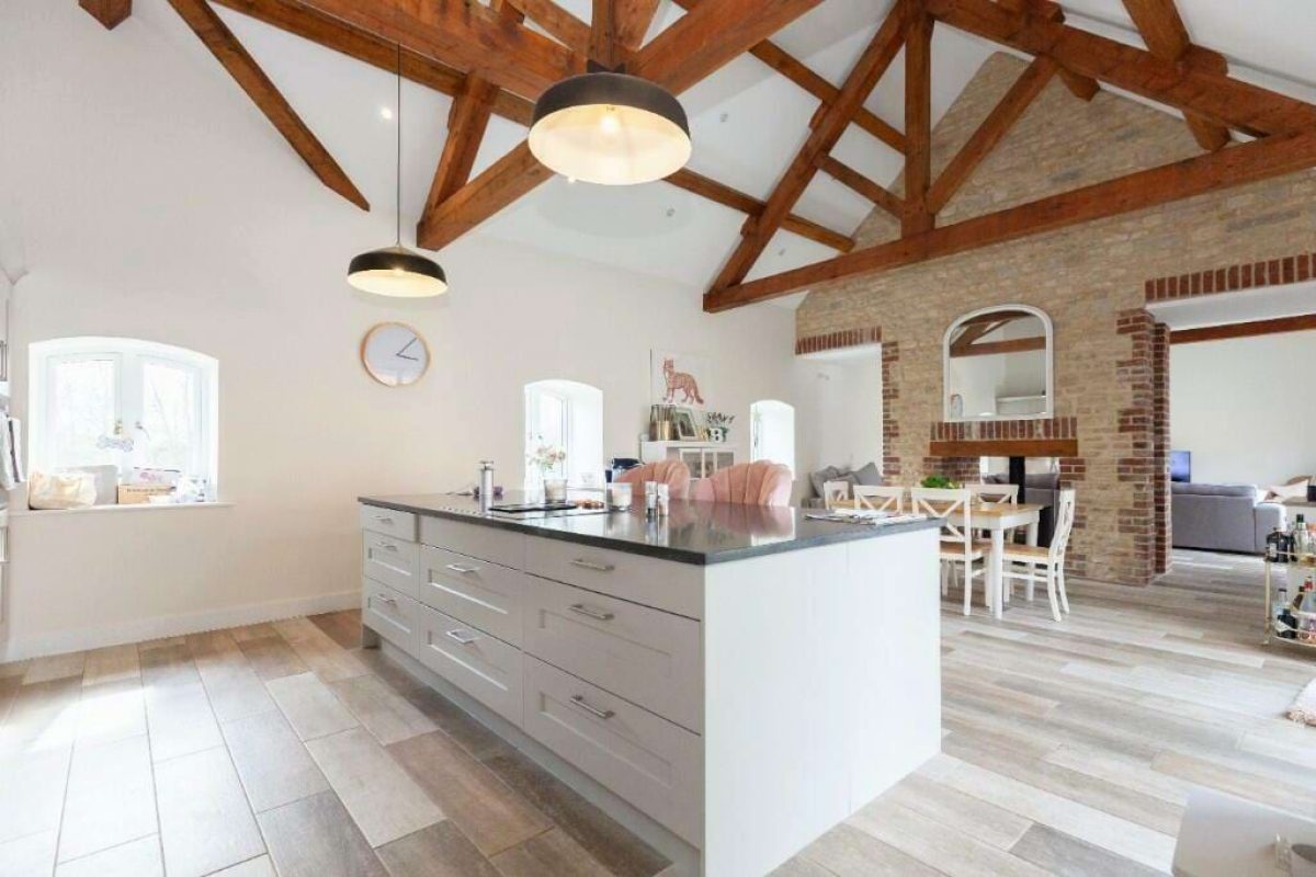 Kitchen at Hordley Farm Barns with a long island under a vaulted ceiling with exposed oak trusses