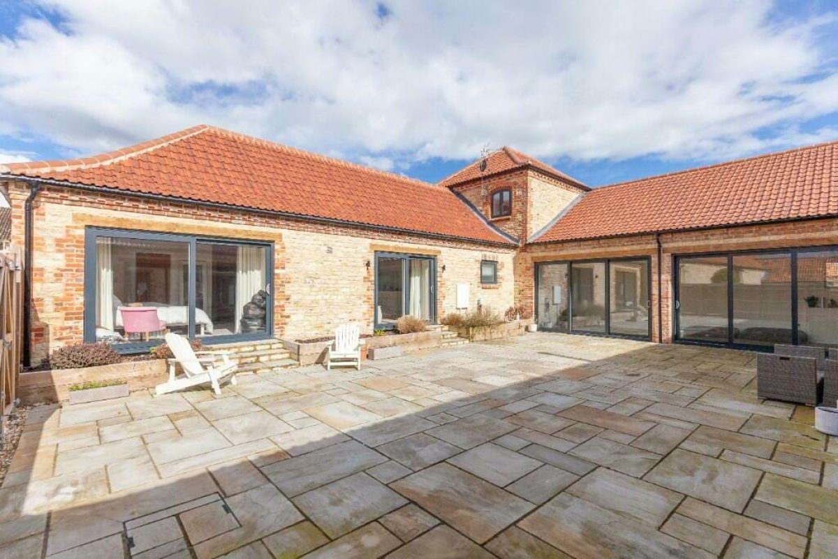 The paved courtyard at Hordley Farm Barns, enclosed by single-storey stone and brick barns with large windows