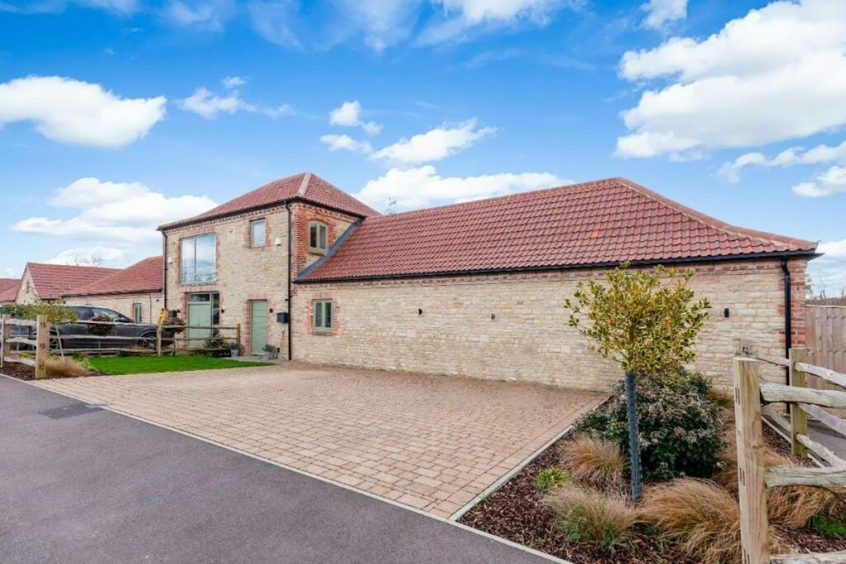 Littleworth Barn, a brick and stone barn conversion with a tiled roof behind a block-paved drive