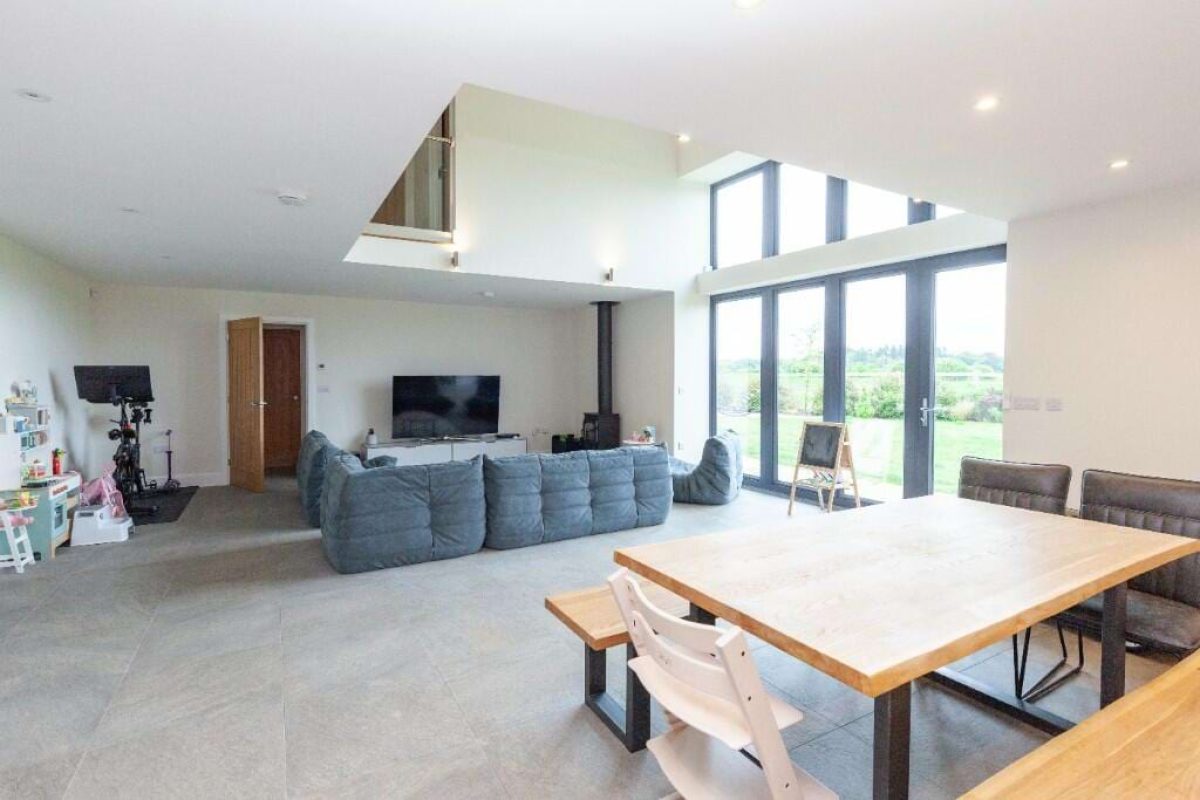 Open-plan living and dining area at Littleworth Barn with a wooden dining table and tall glazed doors