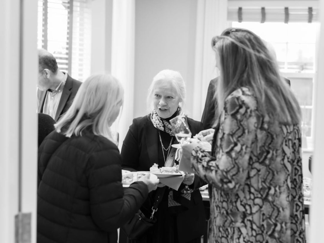 Guests chatting over refreshments after the history talk, in black and white