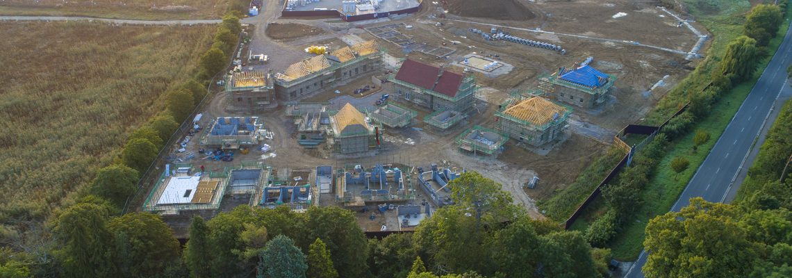 Aerial view of a new housing development under construction, beside a road and open fields