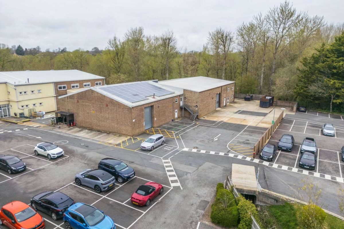 Aerial view of a brick industrial unit with solar panels and parking at Brook Hill