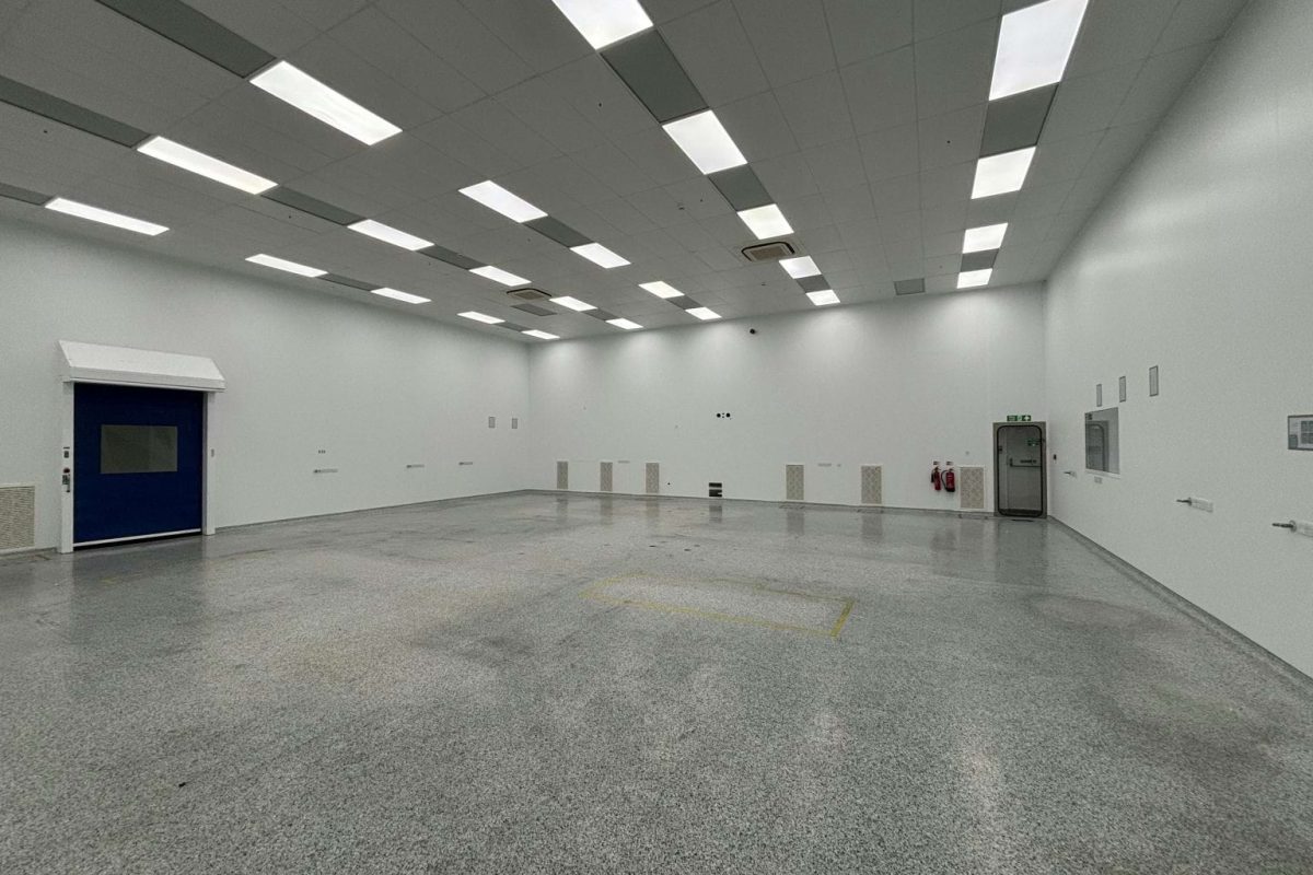 Large empty former clean room at Brook Hill with white walls, a speckled floor and rows of ceiling lights