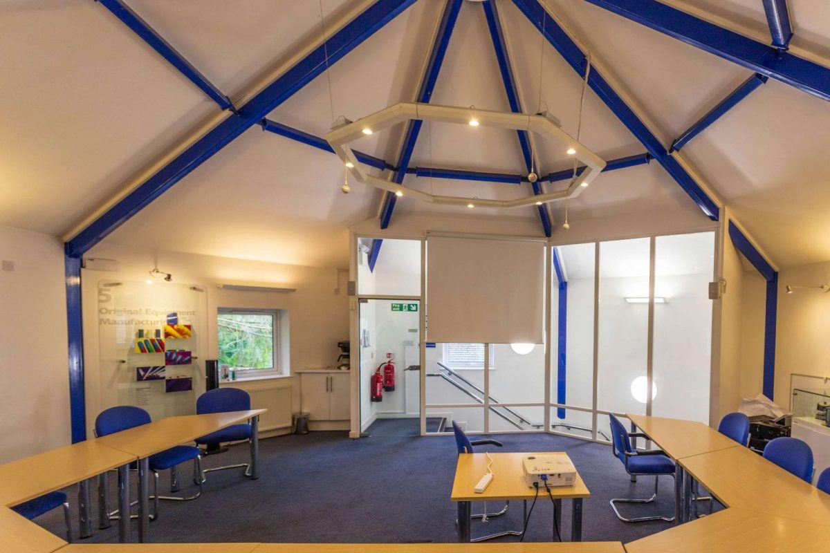 Training room at Brook Hill under a pitched roof with blue steel beams and tables arranged in a U shape