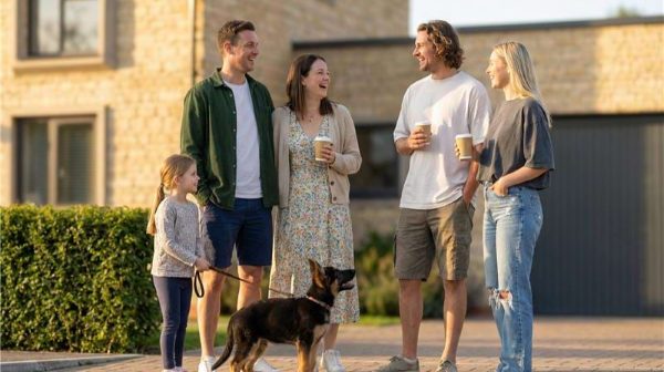 Two couples and a child chatting with coffee cups and a dog outside a stone house at Hill Rise