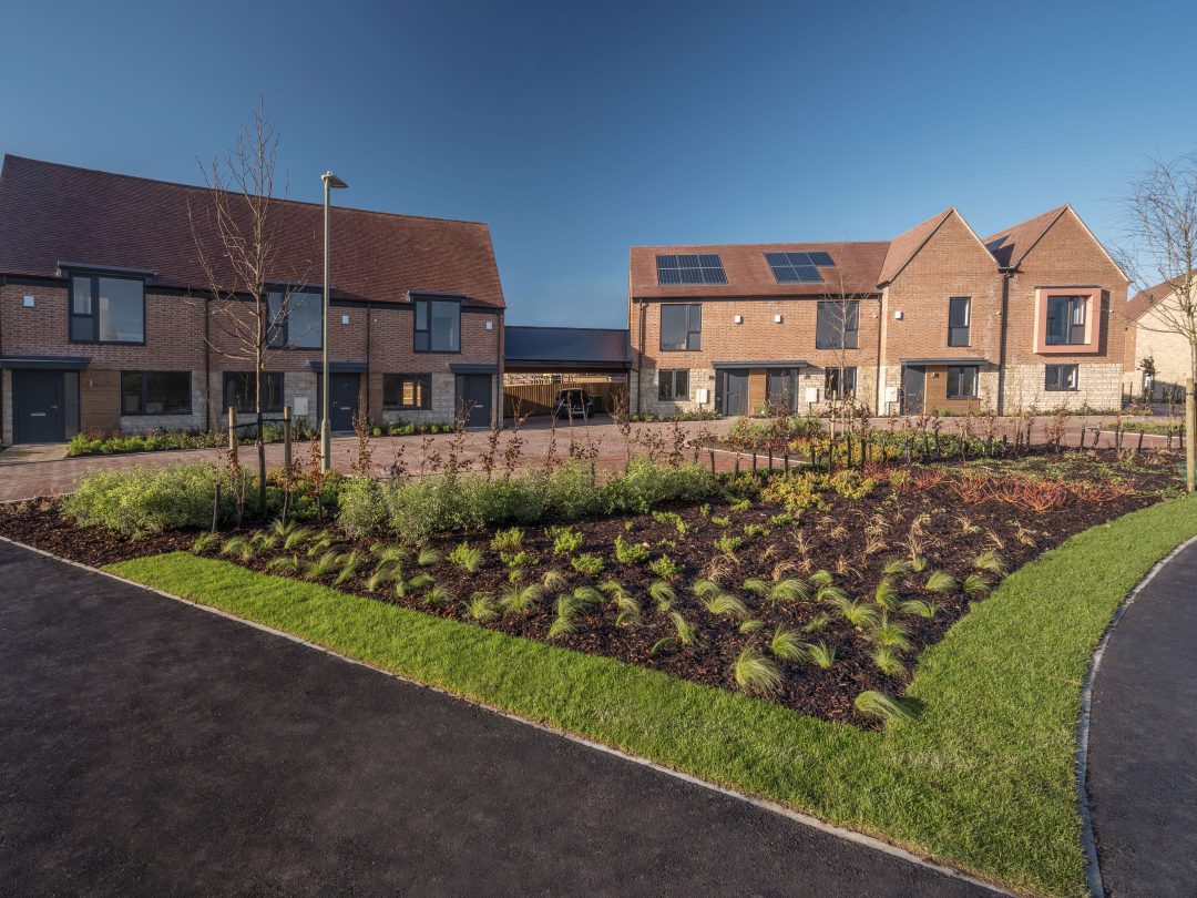 Brick homes with solar panels around a newly planted green at Church Farm