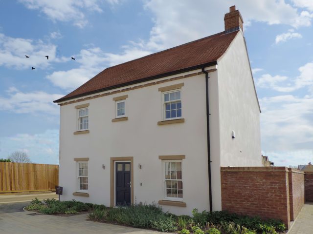 A detached white rendered house with a red tiled roof and stone window surrounds at Park View