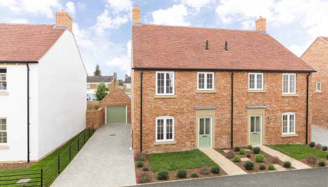 A pair of semi-detached red-brick homes with sage-green doors and front gardens at Park View