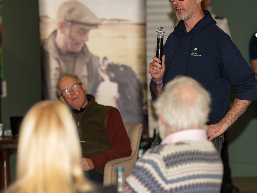 A speaker with a microphone addressing the seated audience at the Estate's farming conference