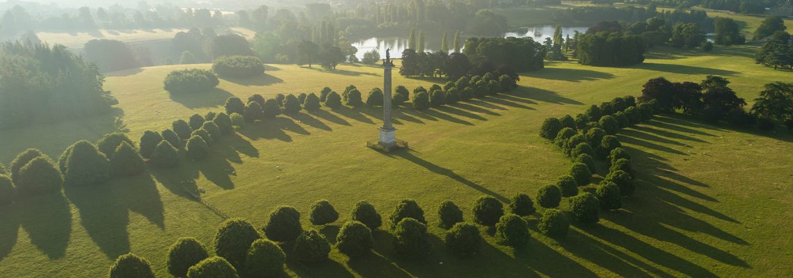 Aerial view of the Column of Victory in Blenheim Park, with avenues of trees and the lake beyond