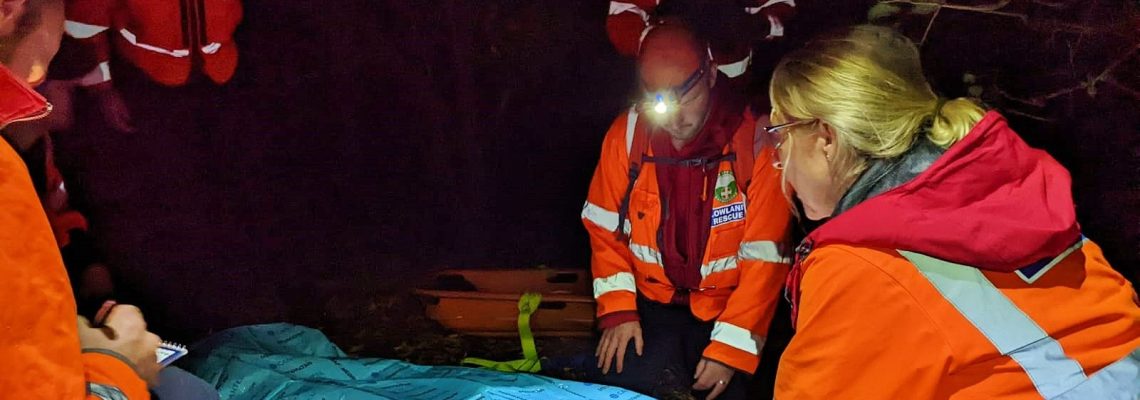 Lowland Rescue volunteers at night lowering a casualty onto a stretcher during a training exercise on the Blenheim Estate