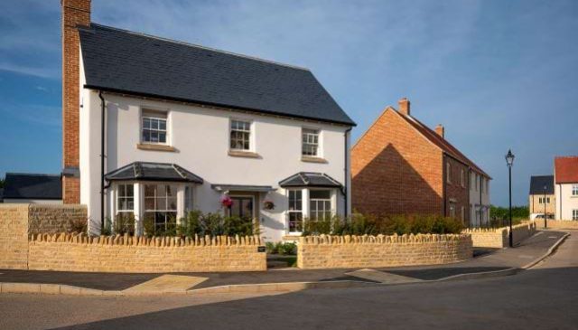A detached white rendered house with bay windows behind a low stone wall at Park View