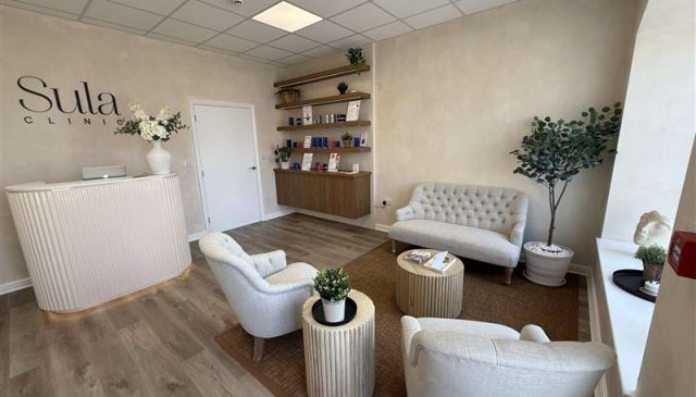 The reception and waiting area inside the Sula Clinic, with cream armchairs and a curved desk