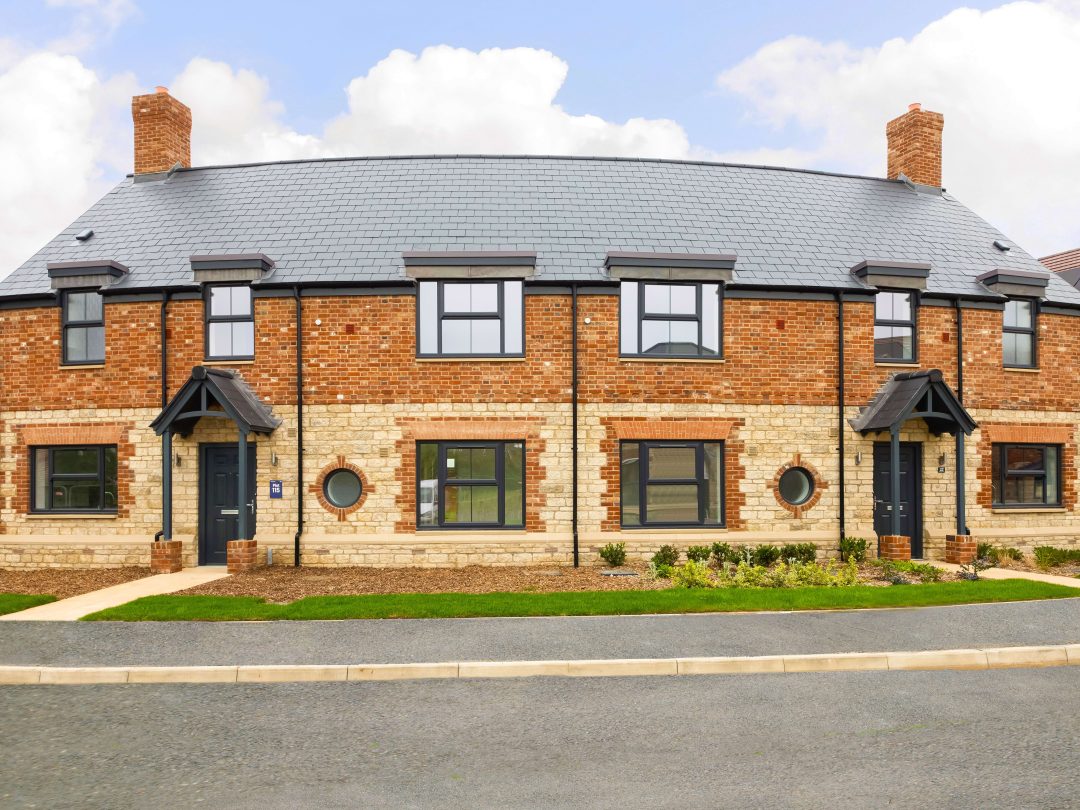 A pair of brick and stone semi-detached homes with porches and round windows at Church Farm