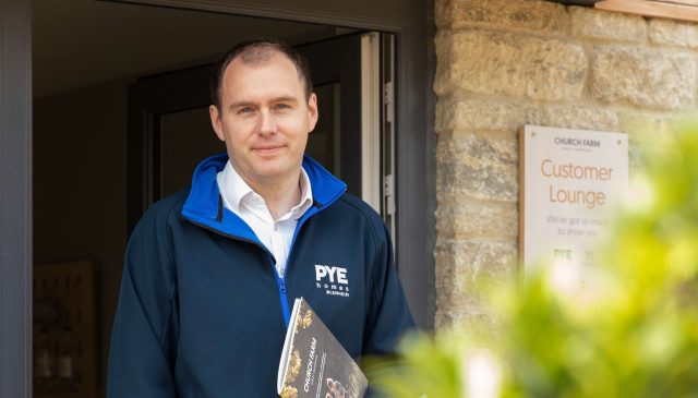 A member of the Pye Homes sales team holding a brochure outside the Church Farm customer lounge
