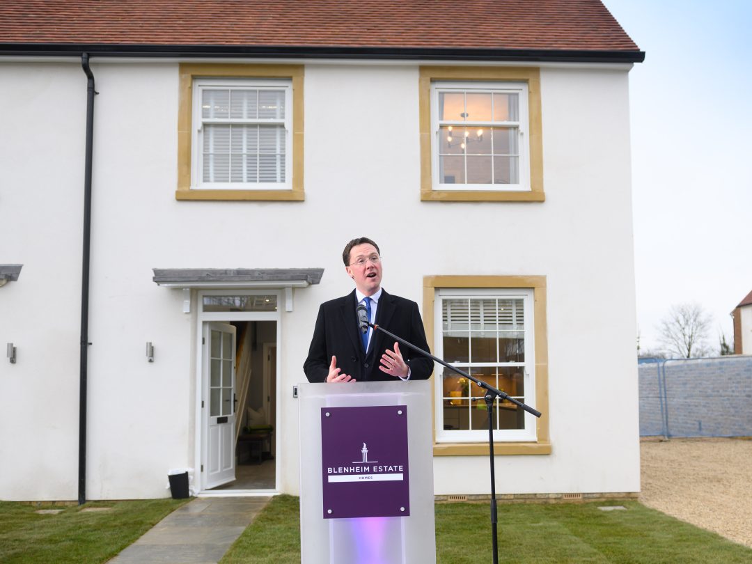 A man speaking at a Blenheim Estate lectern in front of a new house at the Park View opening