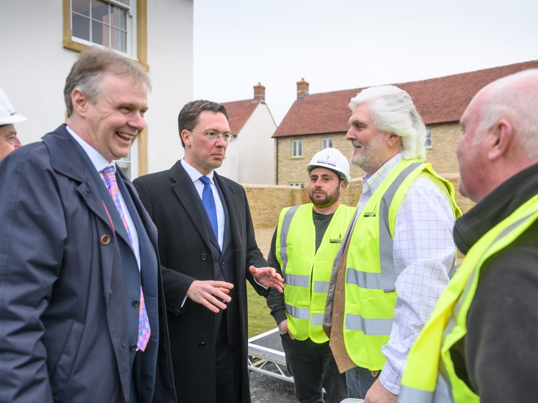 Guests in suits chatting with construction workers in hard hats and hi-vis at the Park View opening