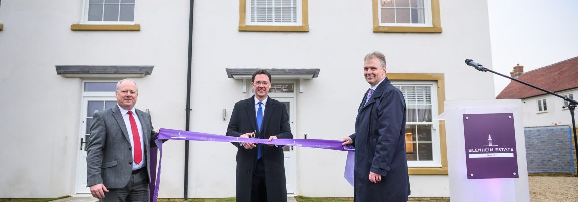 Three men in suits cutting a purple ribbon outside a new house to open Park View