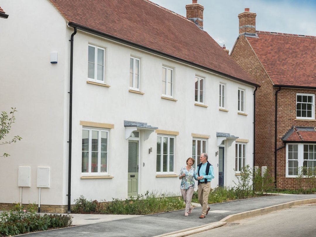 A couple walking past a terrace of white rendered and brick homes at Park View