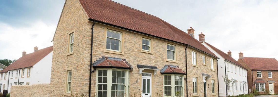 A row of stone, white rendered and brick homes with bay windows along a curving street at Park View