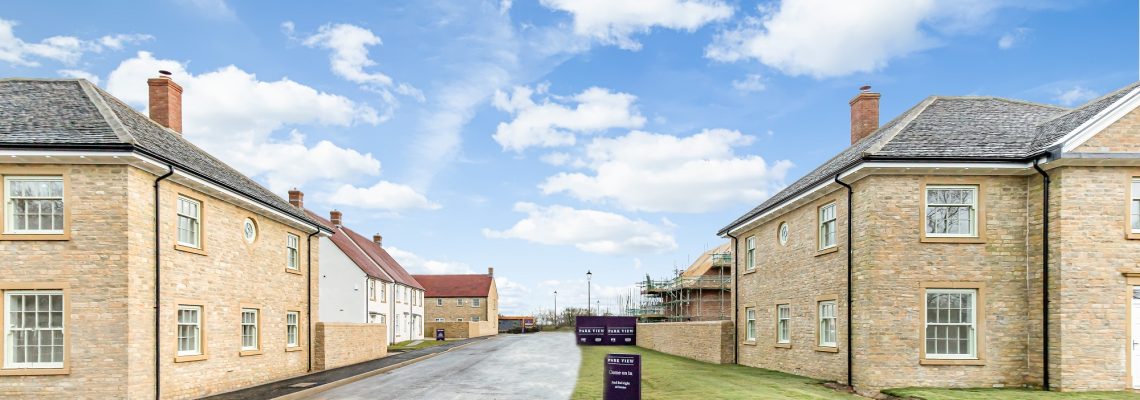 The entrance road into Park View, lined with stone houses and a Blenheim Estate sign