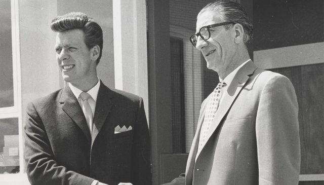 Archive black and white photograph of two men in suits shaking hands, from Minoli's early years
