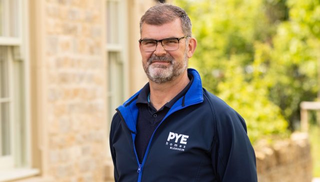 Nigel Pearson of Pye Homes, smiling outside a stone house