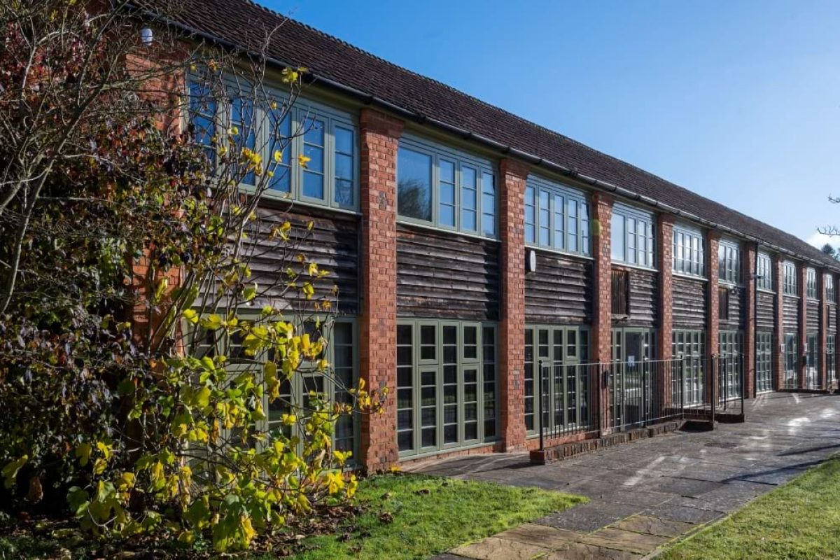 Exterior of the Sawmills offices, a long two-storey brick and timber-clad building with green-framed windows