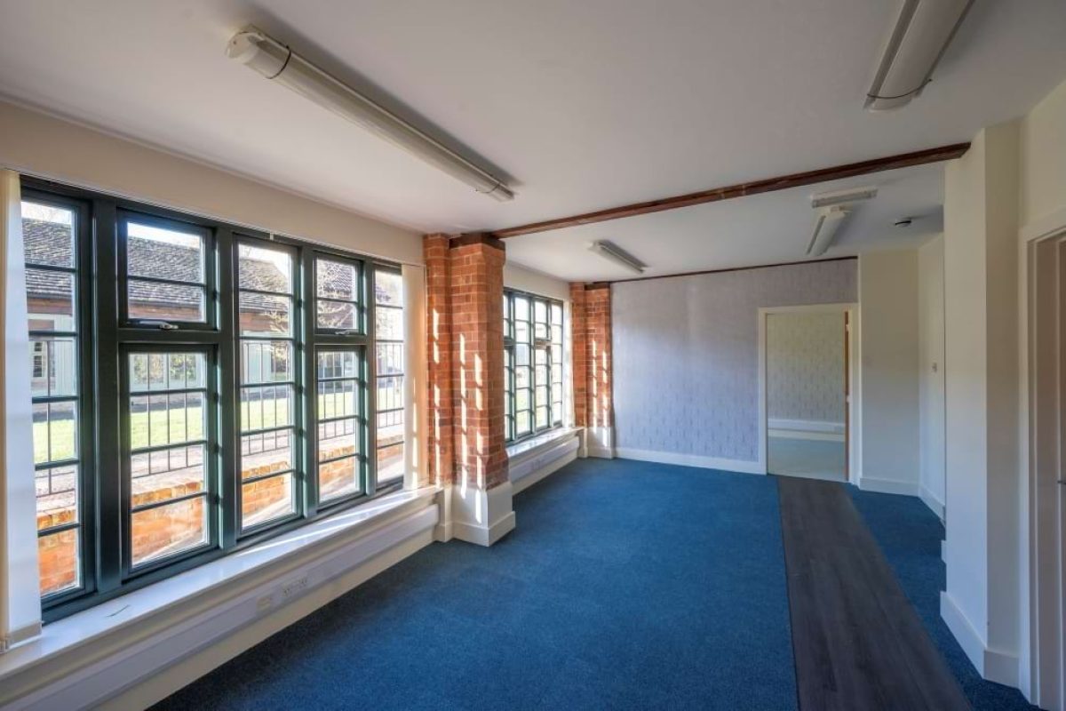 Office space at the Sawmills with blue carpet, exposed brick piers and a long run of green-framed windows