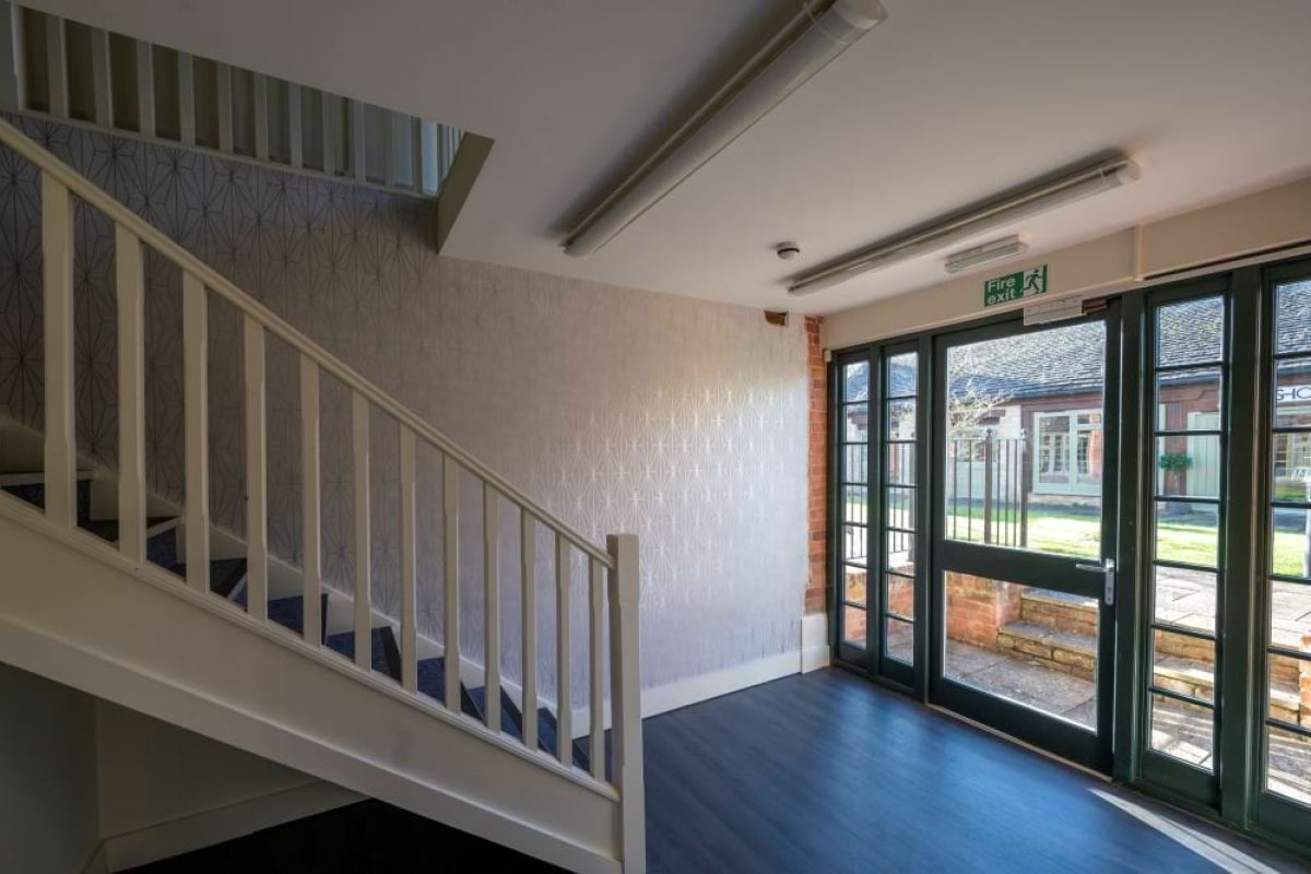 Entrance hall at the Sawmills with a white staircase and glazed double doors opening onto a courtyard