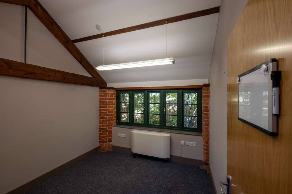 Small office at the Sawmills with exposed beams, a brick-framed window and a whiteboard by the door