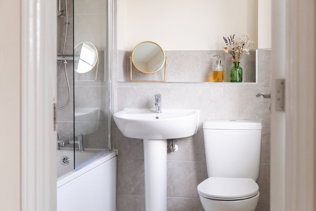 Family bathroom with a white basin, toilet and a bath with a glass shower screen