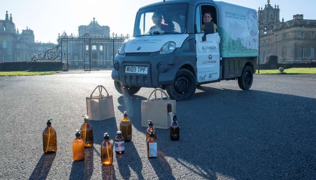 An electric refill van parked at the gates of Blenheim Palace, with refill bottles and bags on the ground