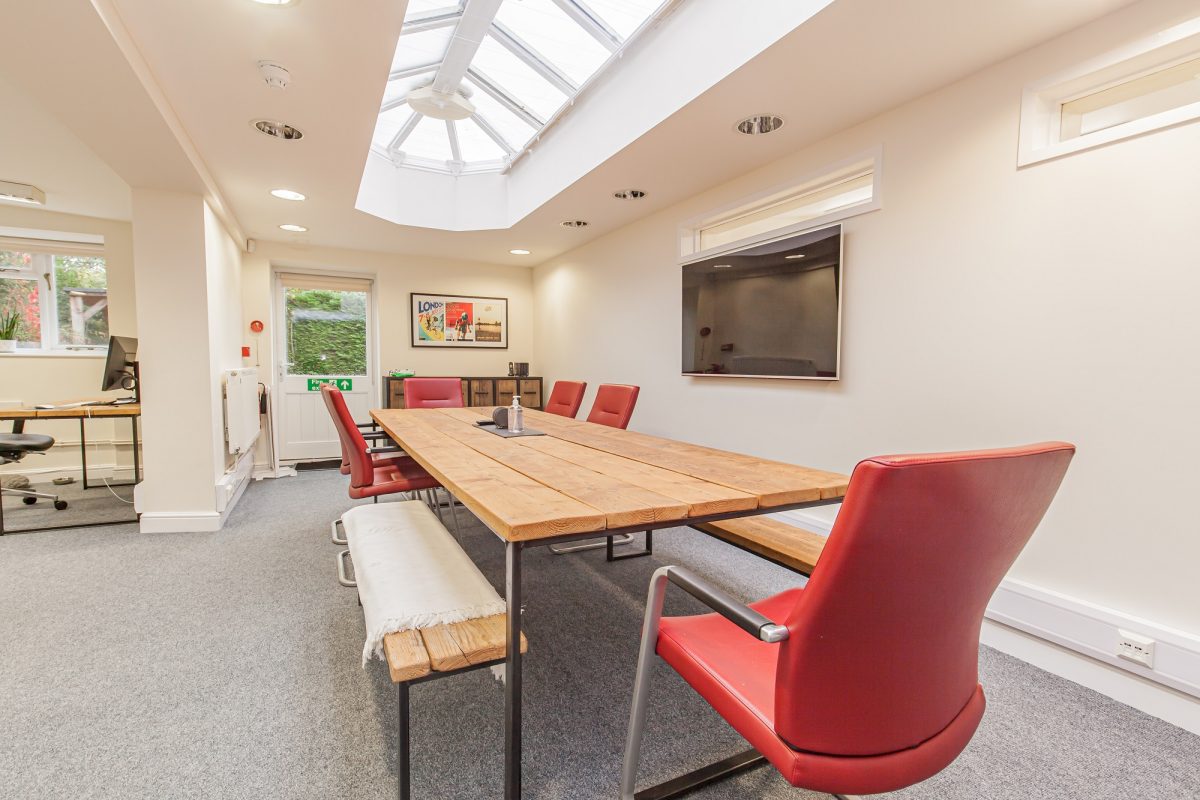 Meeting room in Woodstock Lodge with a long wooden table, red chairs and a glazed roof lantern