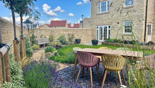 A garden at Park View with a wooden table and chairs, lavender borders and a stone wall